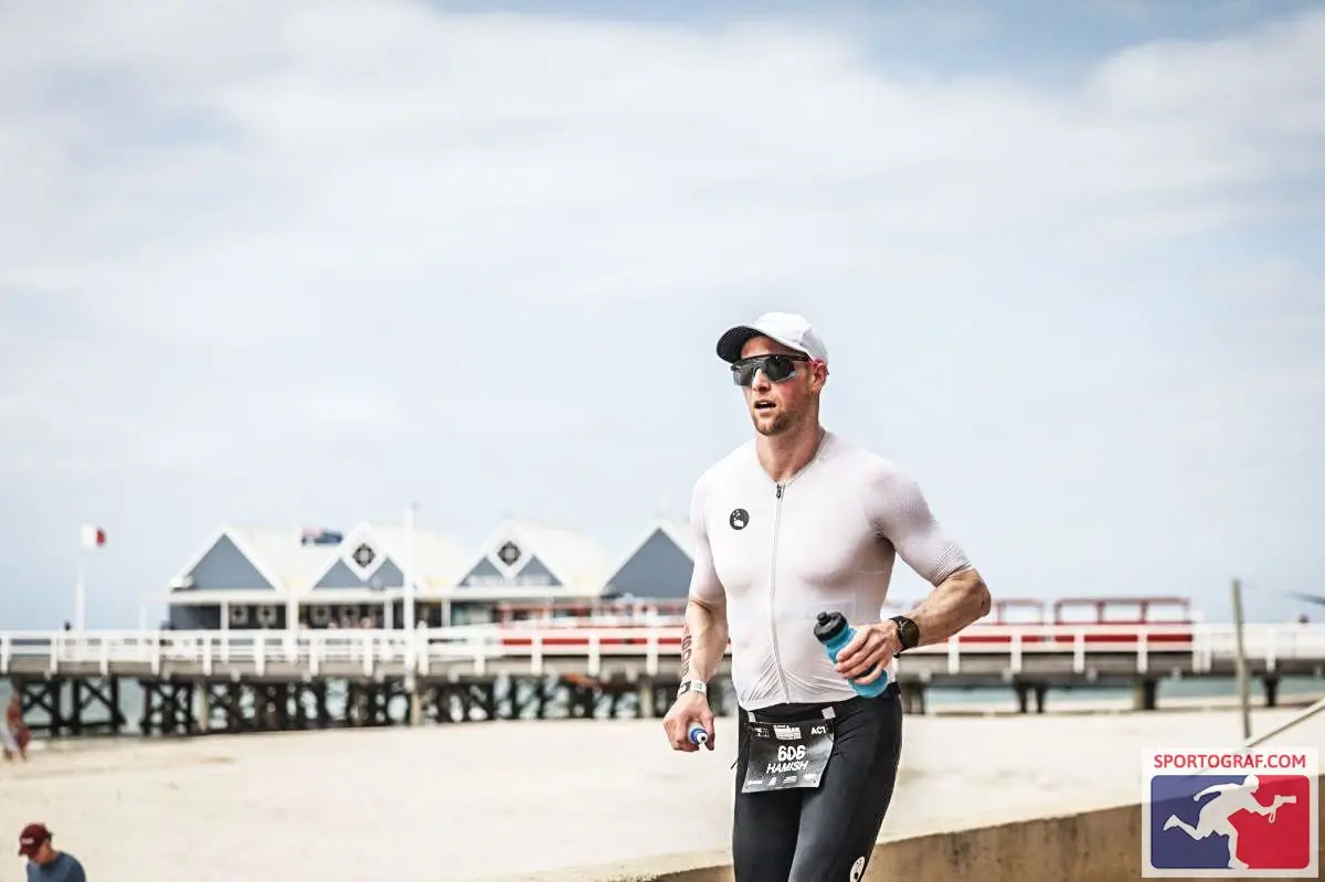 Hamish Armstrong competing in a triathlon, holding a water bottle, showcasing his determination and active lifestyle as the author of Success by 1000 Cuts.